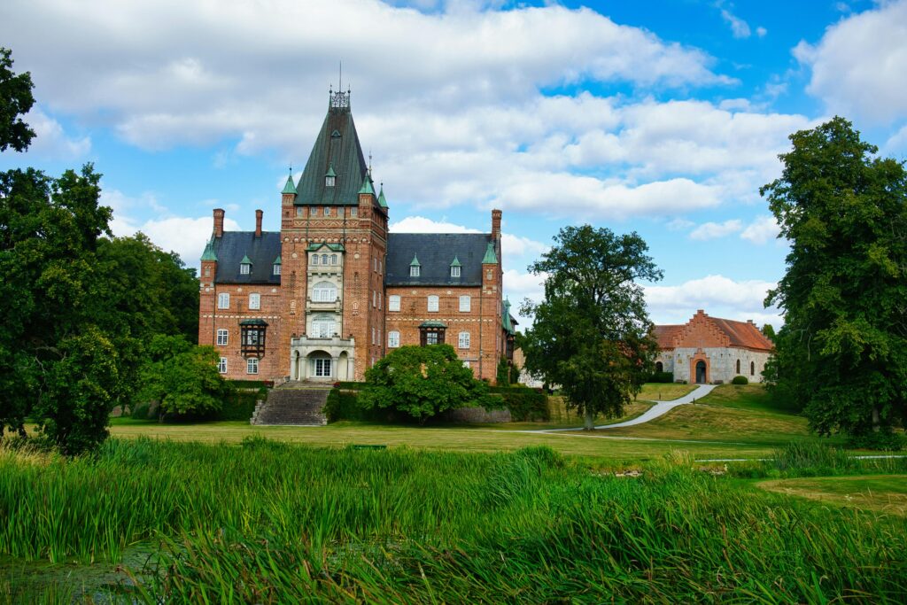 Beautiful Swedish castle in Skåne län surrounded by lush greenery and a clear blue sky.